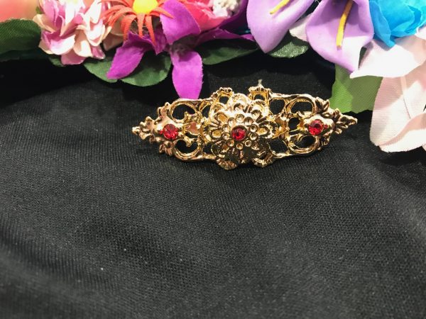 Broche huertana alargado en dorado con flor en relieve y piedras de color para combinar con tu mantón